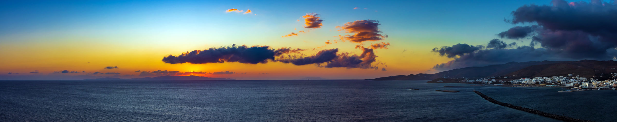 Panorama von Tinos Stadt zum Sonnenuntergang hinter der griechischen Kykladeninsel Syros