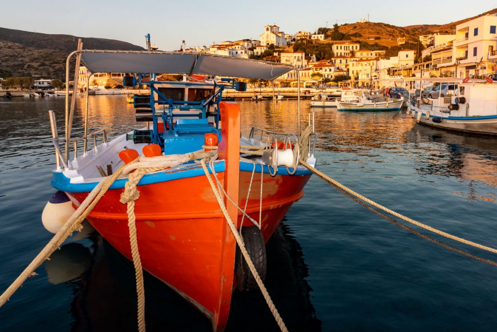 Rotes Fischerboot im abendlichen Hafen des Ferienorts Batsi auf der griechischen Kykladeninsel Andros